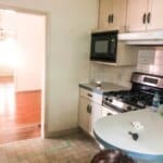 Dimly lit kitchen with a stainless steel stove, off-white cabinets, and a microwave. A person is partially visible at the bottom.