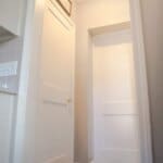 Hallway with a checkered floor, leading to two white doors with a "LAUNDRY" sign above one door and a ceiling light fixture.