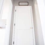 White door under a "Laundry" sign in a hallway with grey walls and black-and-white checkered flooring.