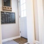 Entryway with white door, wall-mounted chalkboard labeled "Remember," and calendar for February. Black and white checkered floor.
